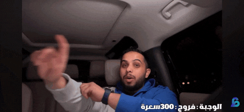 a man sitting in a car with arabic writing on the bottom right