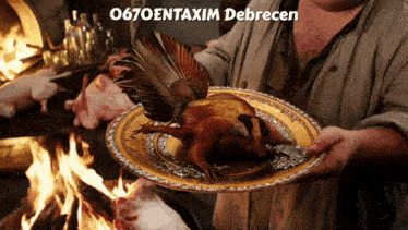 a man is holding a plate with a chicken on it and the words 0670entaxim debrecen behind him