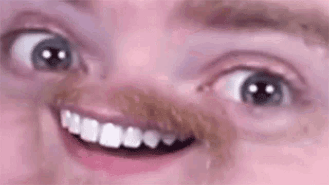 a close up of a man 's face with a mustache and teeth making a funny face .
