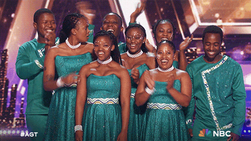 a group of people standing on a stage with the nbc logo in the background