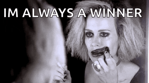 a woman is applying makeup to her face in front of a mirror with the caption im always a winner .