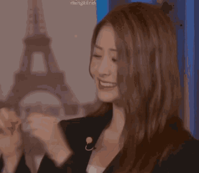 a woman is smiling in front of a picture of the eiffel tower in paris