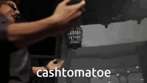 a man is holding a bird cage in his hands and the words cashtomatoe are visible in the background .