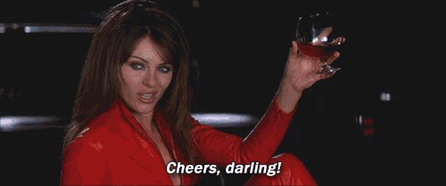 a woman in a red suit is holding a glass with a fireball in it
