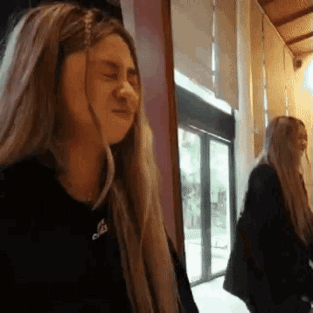 a woman is making a funny face in front of a mirror while another woman looks on .