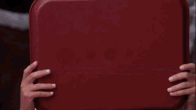 a woman with a lot of food on her face is looking at a red container
