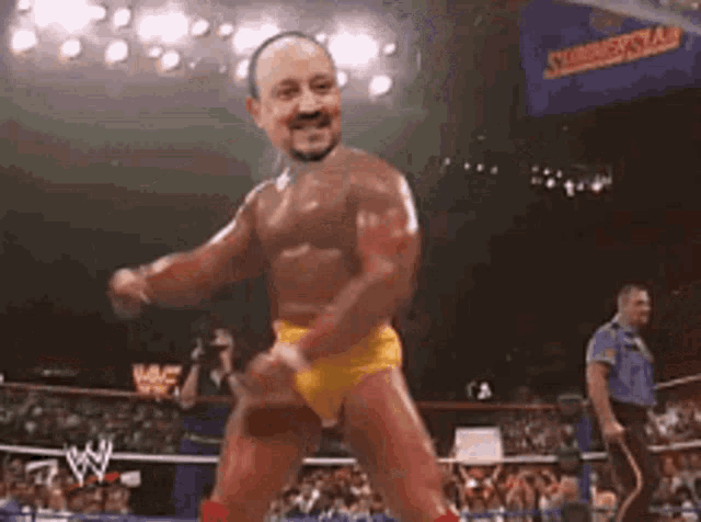 a shirtless wrestler in yellow shorts is dancing in a wrestling ring