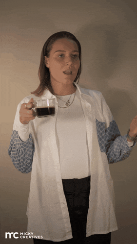 a woman is holding a cup of coffee in front of a micky creatives banner