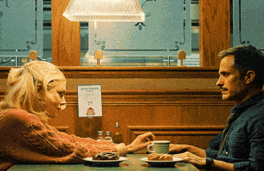 a man and a woman are sitting at a table with plates of food and a sign that says water vendor