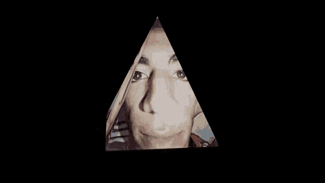 a person 's face is reflected in a triangle with a black background