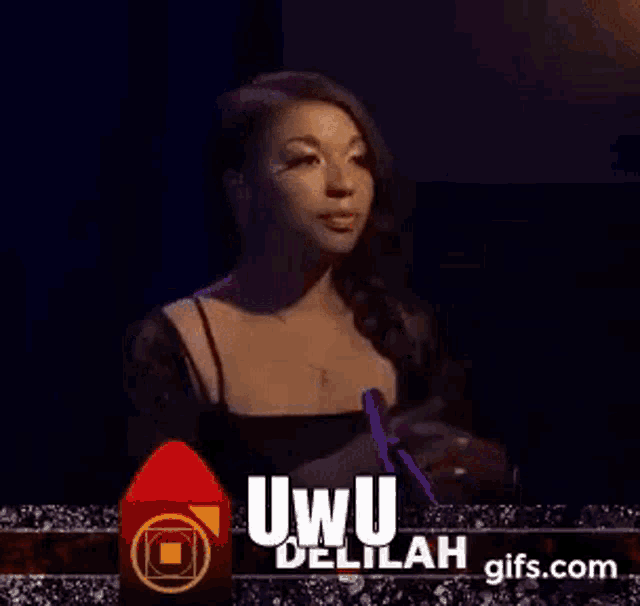 a woman in a black dress is standing in front of a microphone and talking into it .