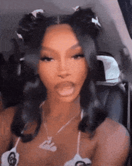 a woman is sitting in the back seat of a car with her mouth open and her hair in buns .