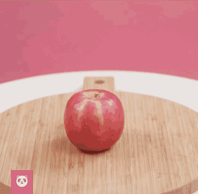 an apple is sitting on a wooden cutting board