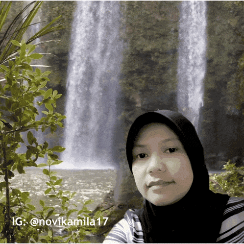 a picture of a woman in front of a waterfall with ig @novikamila17