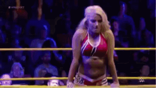 a woman in a bikini is standing in a wrestling ring with a crowd watching .