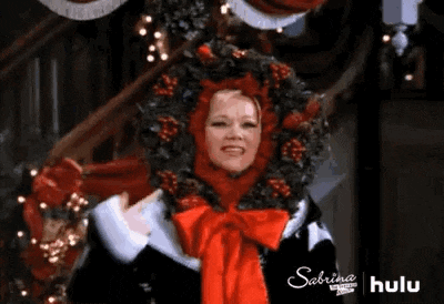 a woman is wearing a christmas wreath on her head and smiling .