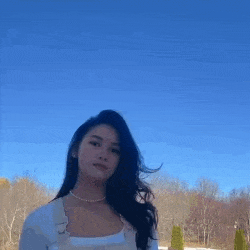a woman is standing in front of a blue sky and the word supreme is on the bottom