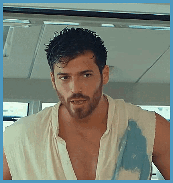 a man with a beard is wearing a white sleeveless shirt