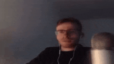 a man with glasses and headphones is sitting in front of a microphone .