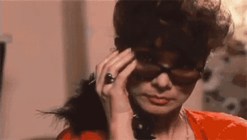 a woman wearing sunglasses and a ring is talking on a telephone .