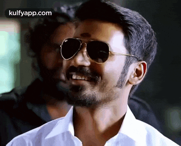 a man with a beard and sunglasses is smiling .