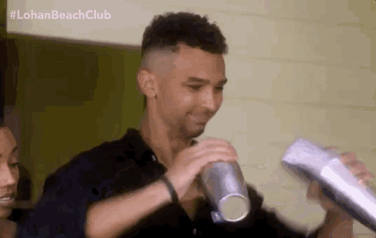 a man is shaking a drink in a shaker while standing next to a woman .