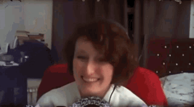 a woman is smiling and making a peace sign while sitting in front of a camera .
