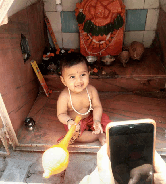 a baby wearing a pearl necklace sits in front of a temple