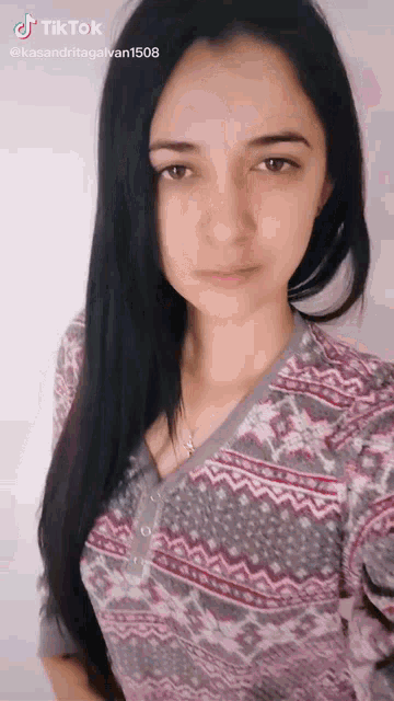 a woman with long black hair is wearing a sweater with a pattern on it ..