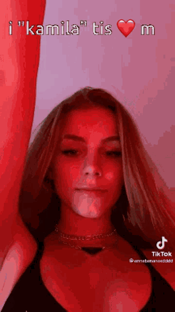 a girl with long blonde hair and a choker looks at the camera in a tiktok video