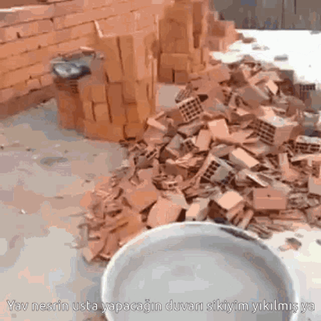 a pile of bricks sits next to a bucket with the words " yav nesrin usta " on it
