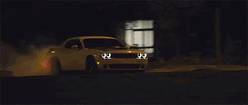 a dodge challenger is driving down the street at night .