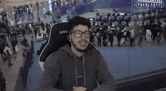 a man wearing glasses is sitting in an arena chair with his fist in the air