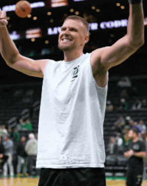 a man in a white tank top holds a basketball in his hand
