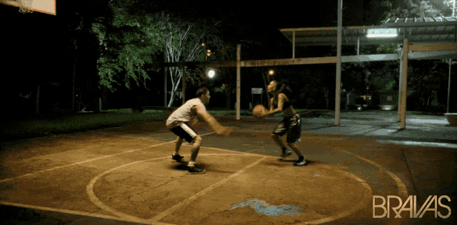 a man and a woman are playing basketball on a court that says bravas on it