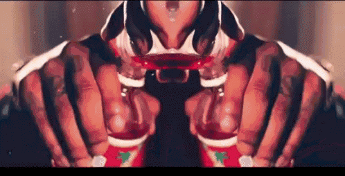 a close up of a person 's hands holding two shot glasses filled with red liquid .