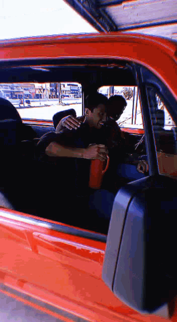 a man in a black shirt is hugging another man in an orange truck