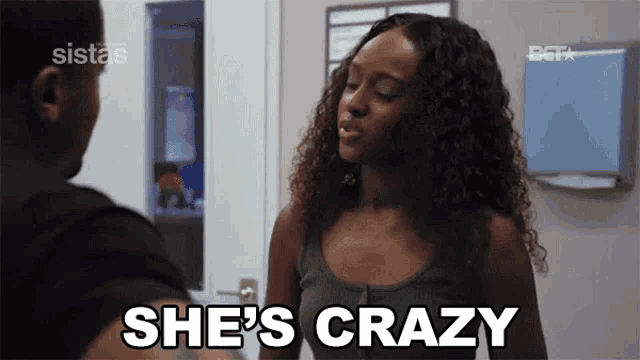 a woman is standing next to a man in a room and says she 's crazy .