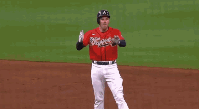 a baseball player wearing a red jersey with the word braves on it is standing on a baseball field .