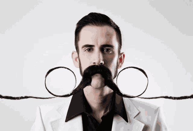 a man with a beard and mustache is wearing a black shirt and a white jacket