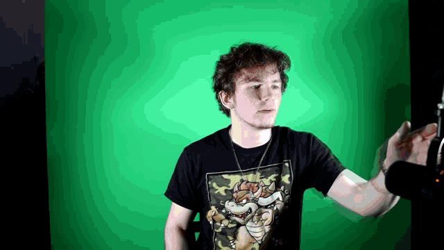 a man wearing a bowser shirt stands in front of a green background