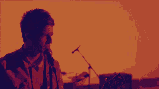 a man playing a guitar in front of a microphone