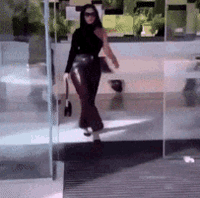 a woman is walking through a glass door with a purse in her hand