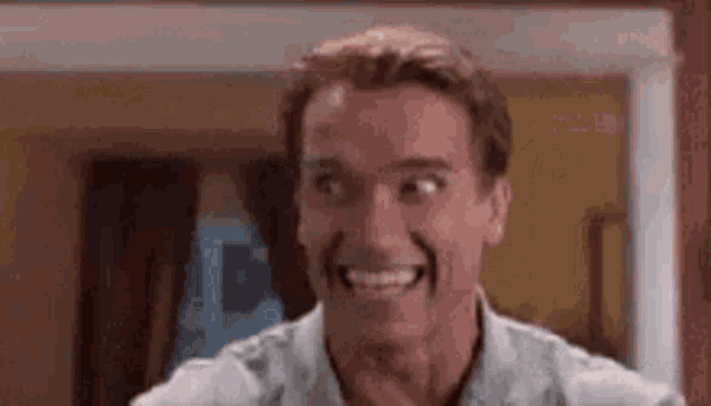 a man is smiling and making a funny face while standing in a room .