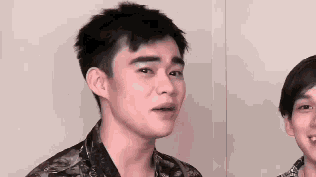 a close up of a young man making a funny face while standing next to another young man .