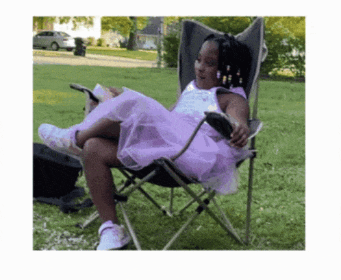a girl in a purple dress is sitting in a chair reading a book