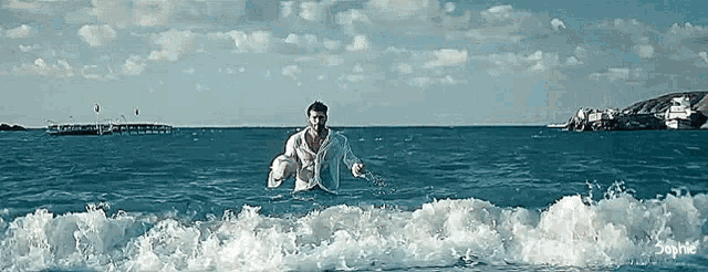 a man in a white shirt is standing in the ocean with the caption sophie