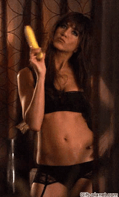 a woman in lingerie is holding a corn on the cob in her hand ..