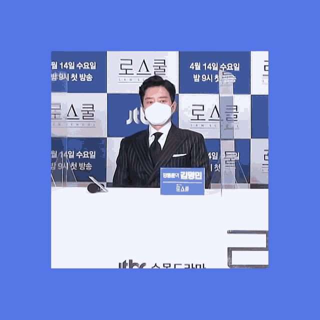 a man wearing a face mask stands in front of a sign that says ' law school '