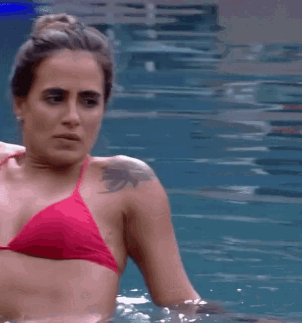 a woman in a red bikini with a tattoo on her arm is swimming in a pool